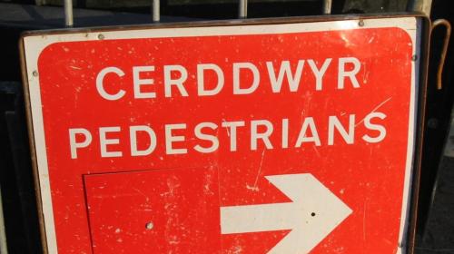 Welsh-English bilingual sign with an arrow pointing to the right