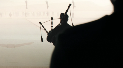 A screenshot from Dune (2021) depicting a bagpipe player descending a ramp.