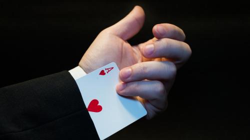 Close-up of a card player's hand, showing a card that the player had hidden up his sleeve.