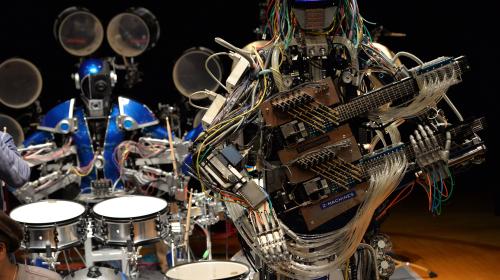 Two robots playing different rock instruments.