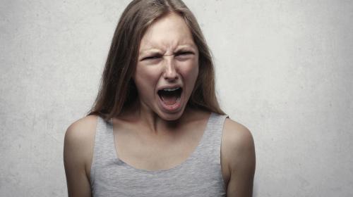 A young woman looking directly at the camera, screaming in terror