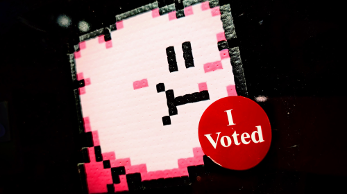 A fuse-bead model of Kirby with an "I Voted" sticker on his chest.