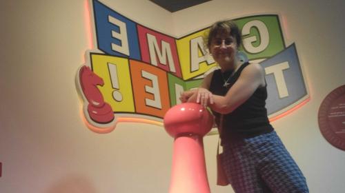 Lydia leaning against a giant red Sorry! pawn at the Strong Museum of Play in Rochester, NY