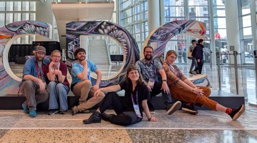 A group photo of your nice hosts and some friends in front of a large GDC sign/display.