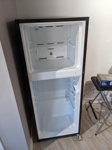 A photo of an empty refrigerator with the doors missing.