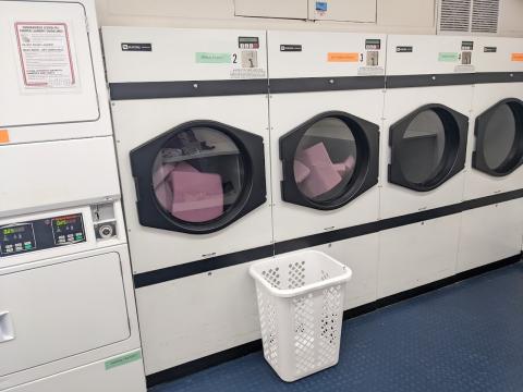 A row of commercial dryers. Two of them are filled with purple foam acoustic panels.